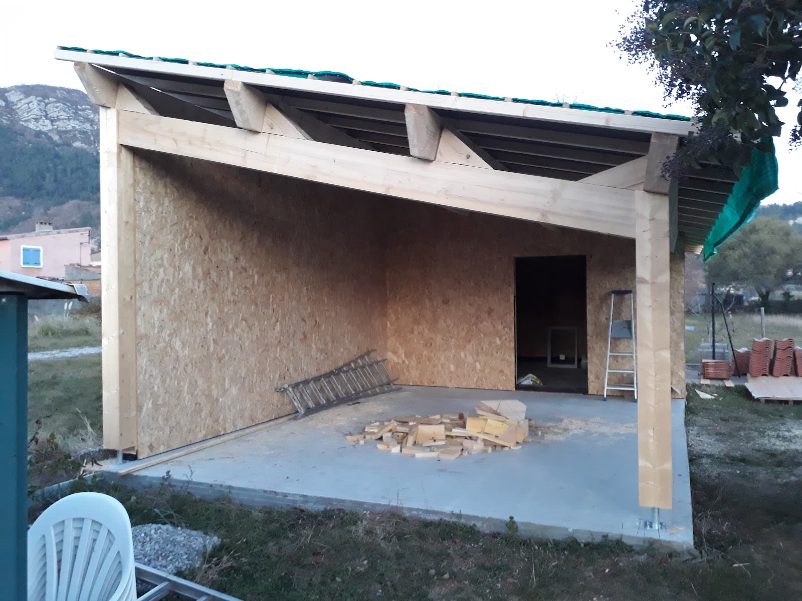 Espace couvert par une structure bois, ouvert sur le jardin